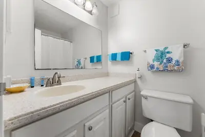 a bathroom with a sink and a mirror and a toilet at Beachfront Studio with Pool & Gulf Views! by Dolce Vita Getaways PCB in Panama City Beach