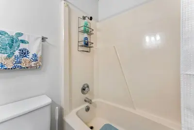 a white bathroom with a shower and a toilet at Beachfront Studio with Pool & Gulf Views! by Dolce Vita Getaways PCB in Panama City Beach