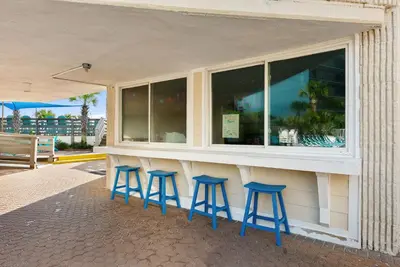 a bar with four blue stools in front of a building at Beachfront Studio with Pool & Gulf Views! by Dolce Vita Getaways PCB in Panama City Beach