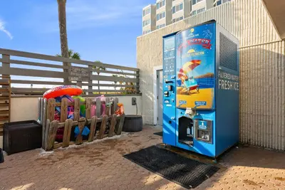 a vending machine next to a fence with an umbrella at Beachfront Studio with Pool & Gulf Views! by Dolce Vita Getaways PCB in Panama City Beach