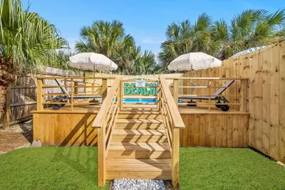 a wooden deck with two chairs on a fence at Disco Dolphin – Your Funky Beachside Haven in PCB in Panama City Beach