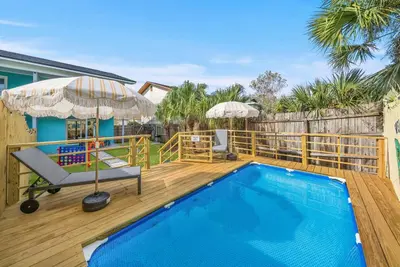 a deck with a pool and a chair and an umbrella at Disco Dolphin – Your Funky Beachside Haven in PCB in Panama City Beach