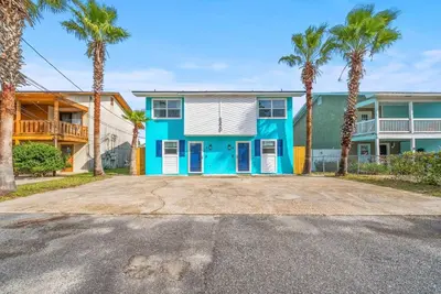 a house with palm trees in front of it at Disco Dolphin – Your Funky Beachside Haven in PCB in Panama City Beach