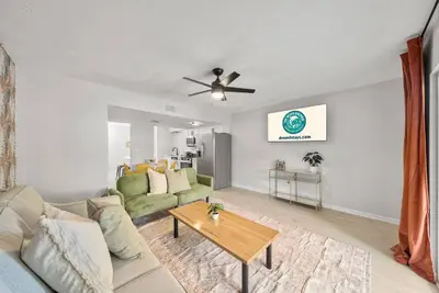 a living room with a couch and a ceiling fan at Disco Dolphin – Your Funky Beachside Haven in PCB in Panama City Beach
