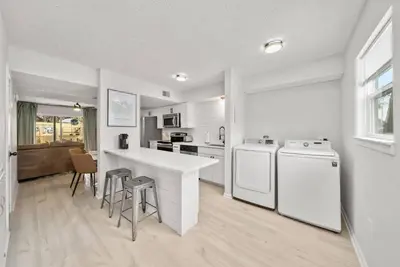 a kitchen with white appliances and a counter with stools at Pool + Games + Outdoor Dining + Walk to the Beach in Panama City Beach