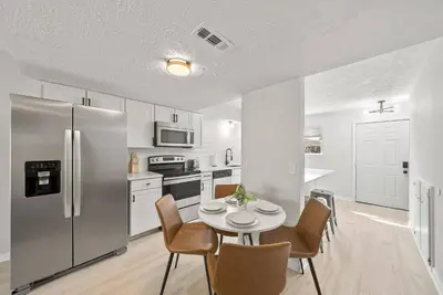 a kitchen with a table and a stainless steel refrigerator at Disco Dolphin Compound | 2x PCB Private Retreats! in Panama City Beach