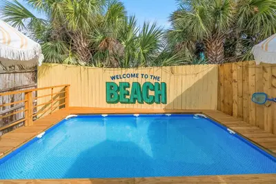 a welcome to the beach sign next to a swimming pool at Disco Dolphin Compound | 2x PCB Private Retreats! in Panama City Beach