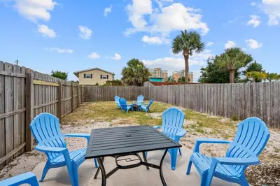 a patio with blue chairs and a table and a fence at Sunset Retreat TOO - 2BR - 4 Min Walk to Beach in Panama City Beach