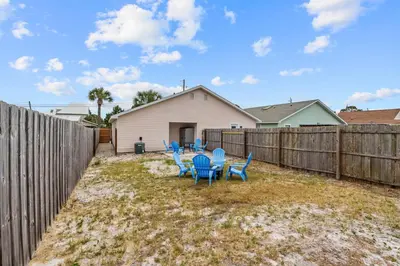 a backyard with blue chairs and a fence at Sunset Retreat TOO - 2BR - 4 Min Walk to Beach in Panama City Beach