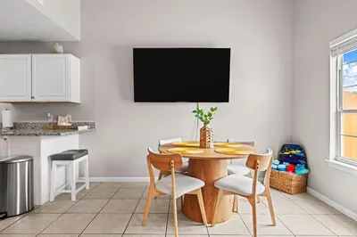 a kitchen with a table with chairs and a tv on the wall at 4 Min Walk to Sand - 2BR - King Bed - Private Yard in Panama City Beach