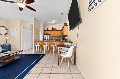a living room and kitchen with a table and chairs at 5 Min Walk to Sand - King Bed - Private Yard in Panama City Beach
