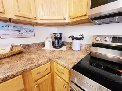 a kitchen counter with a stove and a microwave at 5 Min Walk to Sand - King Bed - Private Yard in Panama City Beach