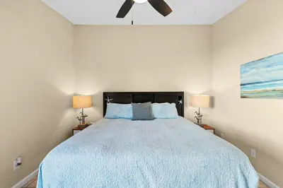 a bedroom with a bed with a blue comforter and two lamps at 5 Min Walk to Sand - King Bed - Private Yard in Panama City Beach