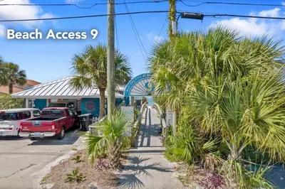 a beach access sign in front of a building with palm trees at The Sand Dollar - King Bed - 6 Min Walk to Beach in Panama City Beach