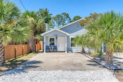a white house with palm trees in front of it at Sunset Dreams - King Bed - 5 Min Walk to Beach in Panama City Beach