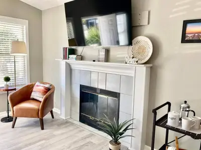 a living room with a fireplace and a chair at Sunset Dreams - King Bed - 5 Min Walk to Beach in Panama City Beach