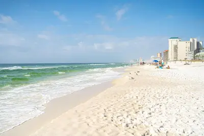 a beach with people and the ocean and buildings at Sunset Dreams - King Bed - 5 Min Walk to Beach in Panama City Beach