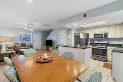 a kitchen and living room with a wooden table and chairs at Family Ready 3BR 2.5BA Home, Near Parks, Shops And Beach in Panama City Beach