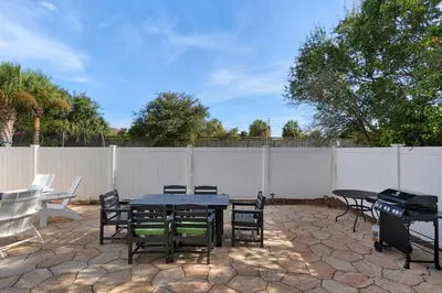 a patio with a table and chairs and a fence at Sunlit Sands in Inlet Beach