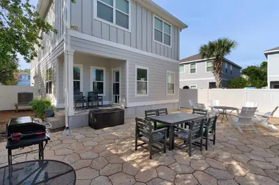 a patio with a table and chairs in front of a house at Sunlit Sands in Inlet Beach