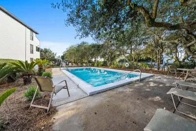 a swimming pool with chairs next to a house at Inlet Dunes 204 l Community Pool l Across From The Beach in Inlet Beach