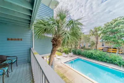 a patio with a palm tree and a swimming pool at Inlet Sands 204 l 1 min walk to beach l Community Pool l Bike to Rosemary in Inlet Beach