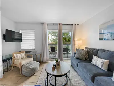 a living room with a couch and a table at Inlet Sands 204 l 1 min walk to beach l Community Pool l Bike to Rosemary in Inlet Beach