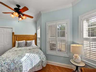 a bedroom with a bed with a ceiling fan and windows at Keylime Pie l Heated Pool l 2 min walk to beach l 6 seater golf cart and 4 bikes included in Inlet Beach