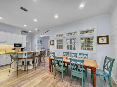 a kitchen and dining room with a wooden table and chairs at Keylime Pie l Heated Pool l 2 min walk to beach l 6 seater golf cart and 4 bikes included in Inlet Beach