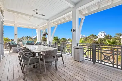 a dining room with a table and chairs on a deck at Pomp in Paradise in Inlet Beach