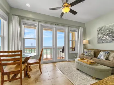 a living room with a ceiling fan and a couch and a table at Leeward 1 7 l Beachfront Condo with Stunning Views of the Water l Bike to Seaside in Seagrove Beach