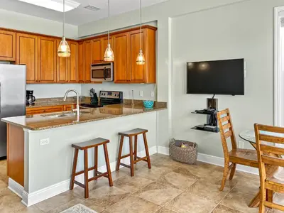 a kitchen with wooden cabinets and a counter with bar stools at Leeward 1 7 l Beachfront Condo with Stunning Views of the Water l Bike to Seaside in Seagrove Beach