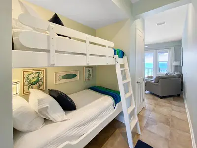 a bedroom with two bunk beds and a living room at Leeward 1 7 l Beachfront Condo with Stunning Views of the Water l Bike to Seaside in Seagrove Beach