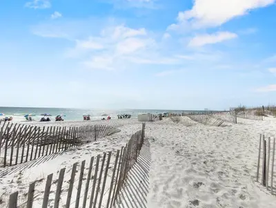 a fence on a beach with the ocean in the background at Leeward II 3 l Beachfront Condo l Large first level deck with steps down to sand in Seagrove Beach