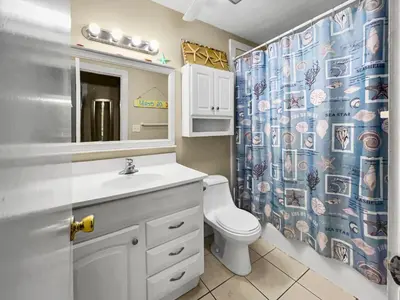 a bathroom with a sink and a toilet and a shower curtain at Leeward II 3 l Beachfront Condo l Large first level deck with steps down to sand in Seagrove Beach