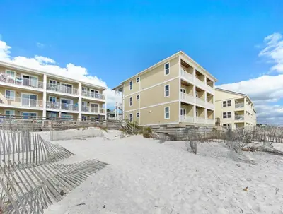 a building on the beach in front of condos at Leeward II 3 l Beachfront Condo l Large first level deck with steps down to sand in Seagrove Beach
