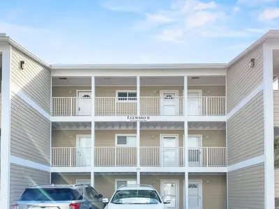 two cars parked in front of a building at Leeward II 3 l Beachfront Condo l Large first level deck with steps down to sand in Seagrove Beach