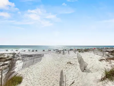 a beach with chairs and umbrellas and the ocean at Leeward II 3 l Beachfront Condo l Large first level deck with steps down to sand in Seagrove Beach