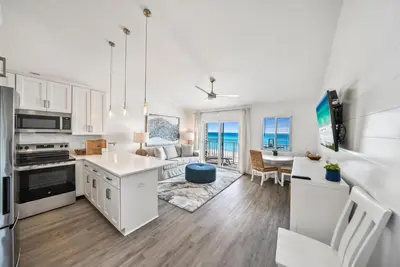 a kitchen and living room with white cabinets at Leeward II 8 Sand Angels l Beachfront Condo l Newly Renovated l Beach Towels in Seagrove Beach