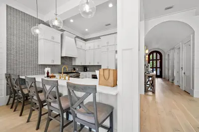 a kitchen with white cabinets and a large island with chairs at Magnolia Tides l 6 Bedroom l Private Pool l South of 30A l Santa Rosa Beach in Santa Rosa Beach