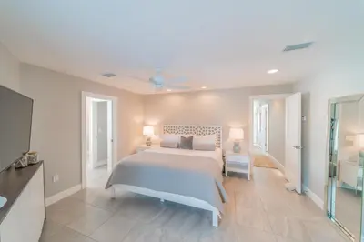 a white bedroom with a bed and a bathroom at Nifty Shades of Gray l Beachfront and panoramic Views l Fire pit beachside l 4 Bikes in Inlet Beach