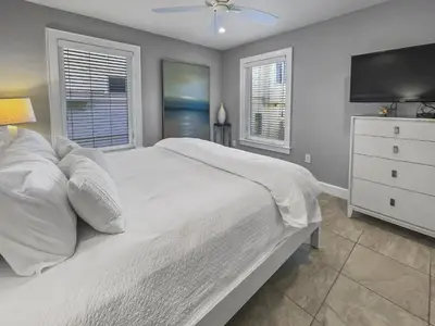 a bedroom with a white bed and a tv at Nifty Shades of Gray l Beachfront and panoramic Views l Fire pit beachside l 4 Bikes in Inlet Beach