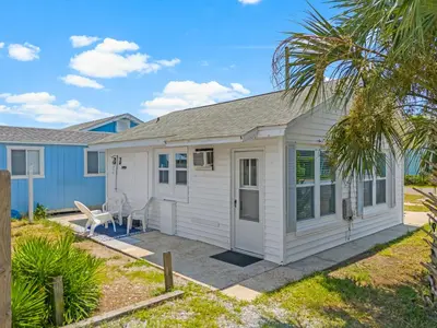 a small white cottage with a palm tree at 19224 Delmar Dr in Panama City Beach
