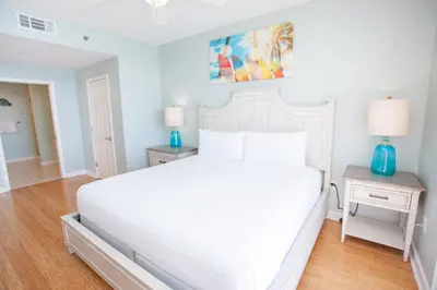 a white bed in a bedroom with two night stands at Splash 1701E in Panama City Beach