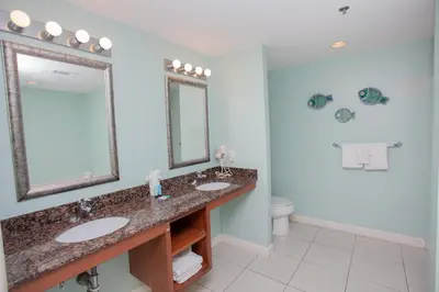 a bathroom with two sinks and a mirror and a toilet at Splash 1701E in Panama City Beach