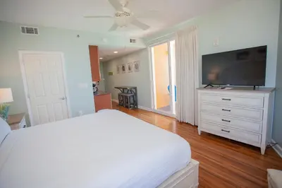a bedroom with a white bed and a flat screen tv at Splash 1701E - Studio in Panama City Beach