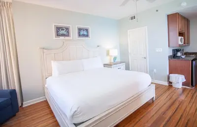 a bedroom with a large white bed and a kitchen at Splash 1701E - Studio in Panama City Beach