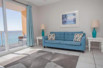 a living room with a blue couch and a balcony at Splash 504E in Panama City Beach