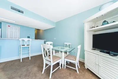 a dining room with a table and chairs and a tv at Majestic Beach Towers One 1314 by Emerald Coast Retreats in Panama City Beach