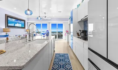 a kitchen with white cabinets and a blue rug at Memories at the Seashore in Panama City Beach